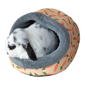 White and black rabbit in a hooded bed with carrot design and grey trim.