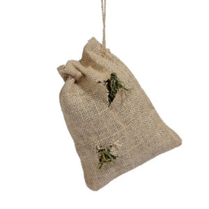 A small jute bag with a drawstring and two small holes cut in the side, alloiwing side, allowing hay to peek out.